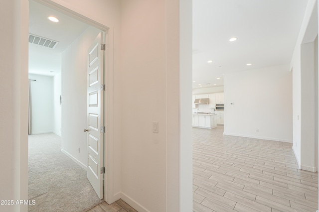 corridor featuring light colored carpet