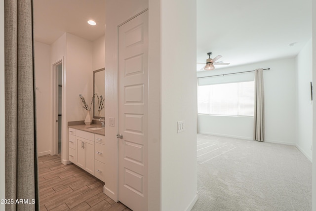 hallway featuring light colored carpet and sink