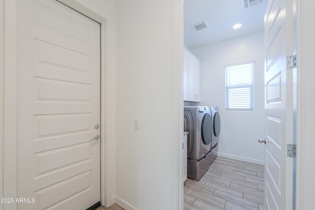 clothes washing area featuring cabinets and washing machine and clothes dryer