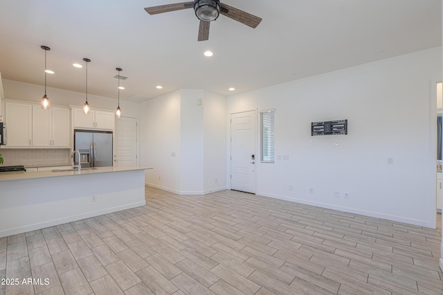 kitchen featuring ceiling fan, sink, stainless steel fridge with ice dispenser, decorative light fixtures, and white cabinets