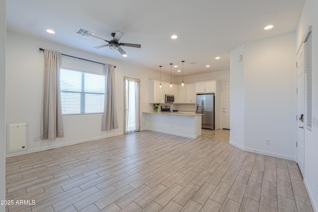 kitchen featuring kitchen peninsula, stainless steel appliances, ceiling fan, decorative light fixtures, and white cabinetry