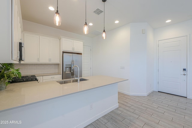 kitchen with white cabinets, sink, stainless steel refrigerator with ice dispenser, decorative light fixtures, and gas stove