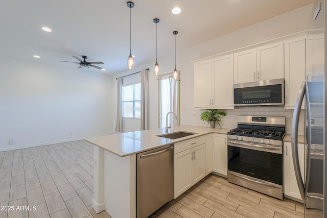 kitchen featuring kitchen peninsula, white cabinetry, sink, and appliances with stainless steel finishes