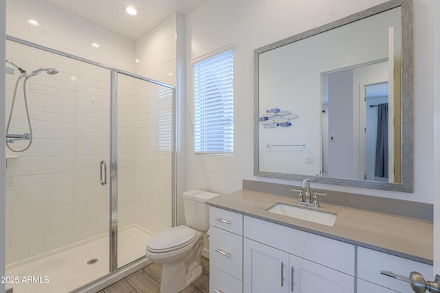 bathroom with a shower with door, vanity, and toilet