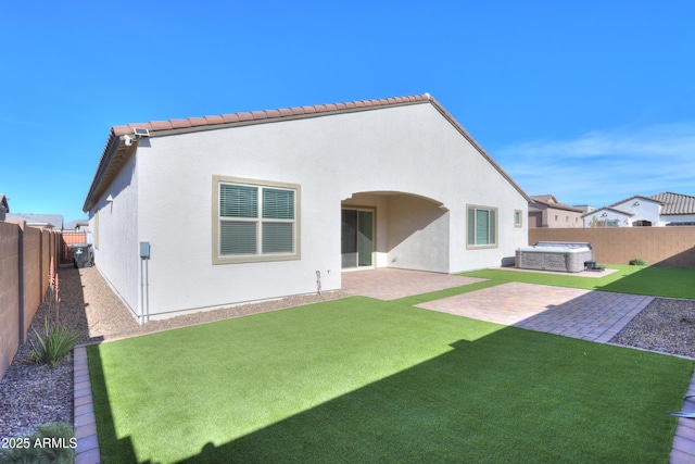 back of house with a yard, a patio, and a hot tub