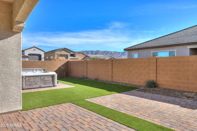 view of yard with a mountain view, a patio, and a hot tub