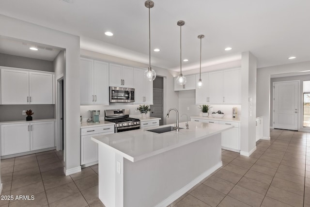 kitchen featuring stainless steel appliances, white cabinetry, sink, and an island with sink