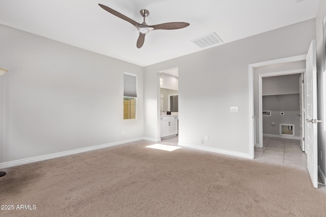 unfurnished bedroom featuring ceiling fan, light colored carpet, and ensuite bath