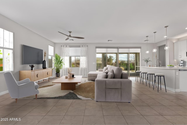 tiled living room featuring ceiling fan and sink