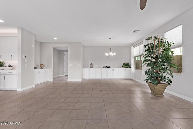 unfurnished living room with an inviting chandelier and light tile patterned floors