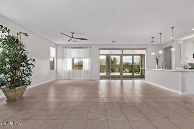 unfurnished living room featuring sink, light tile patterned floors, and ceiling fan