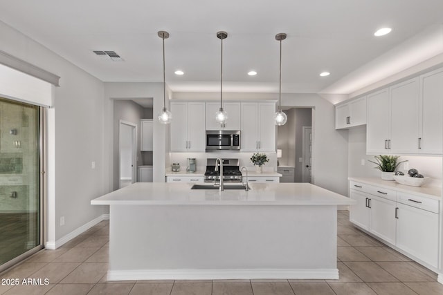 kitchen with white cabinetry, appliances with stainless steel finishes, sink, and a center island with sink