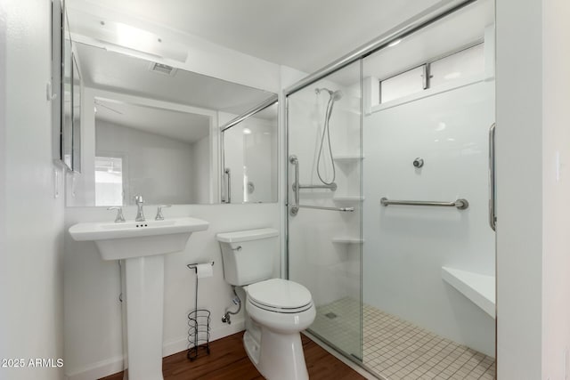 bathroom with toilet, hardwood / wood-style floors, vaulted ceiling, and a shower with shower door