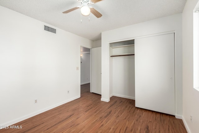 unfurnished bedroom with a closet, ceiling fan, hardwood / wood-style floors, and a textured ceiling