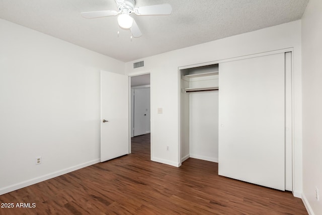 unfurnished bedroom featuring a textured ceiling, a closet, ceiling fan, and dark hardwood / wood-style flooring