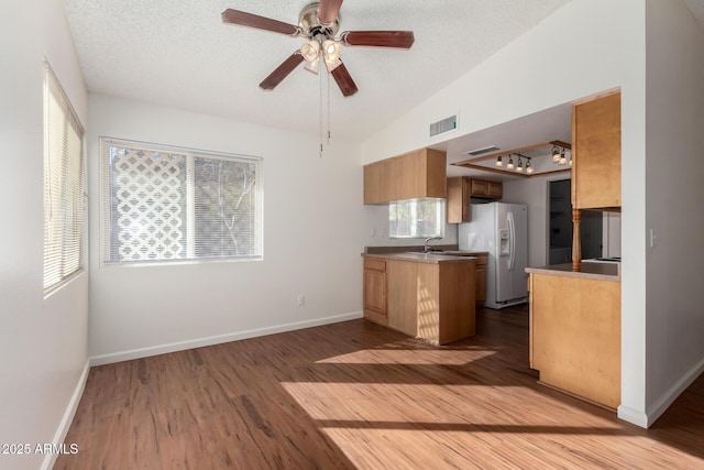 kitchen with ceiling fan, dark wood-type flooring, white fridge with ice dispenser, a textured ceiling, and lofted ceiling