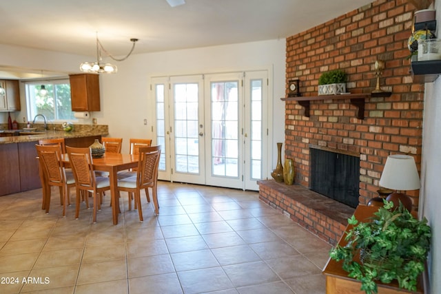 dining area with a notable chandelier, light tile patterned floors, french doors, and a brick fireplace