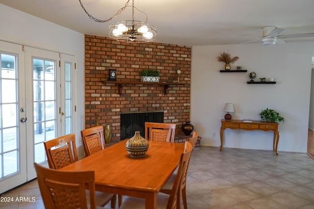 dining room featuring a fireplace, french doors, and ceiling fan with notable chandelier