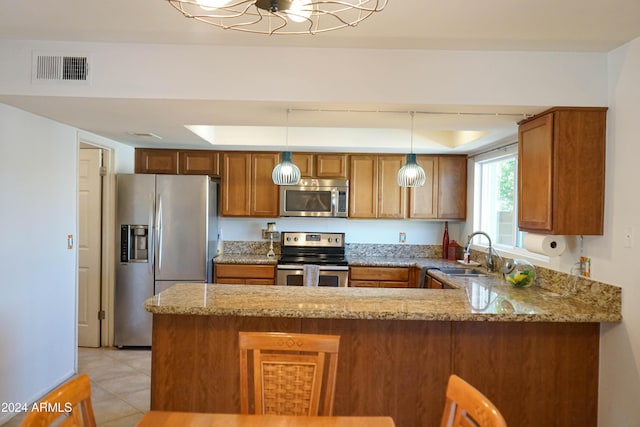 kitchen featuring light stone countertops, sink, kitchen peninsula, decorative light fixtures, and appliances with stainless steel finishes