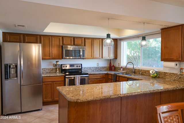 kitchen with light stone countertops, sink, kitchen peninsula, pendant lighting, and appliances with stainless steel finishes