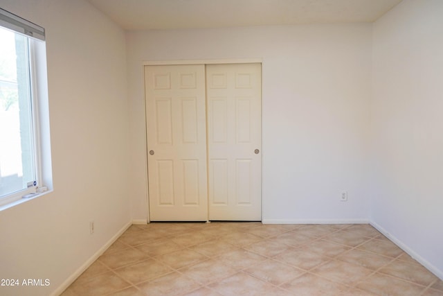 unfurnished bedroom with a closet, multiple windows, and light tile patterned flooring