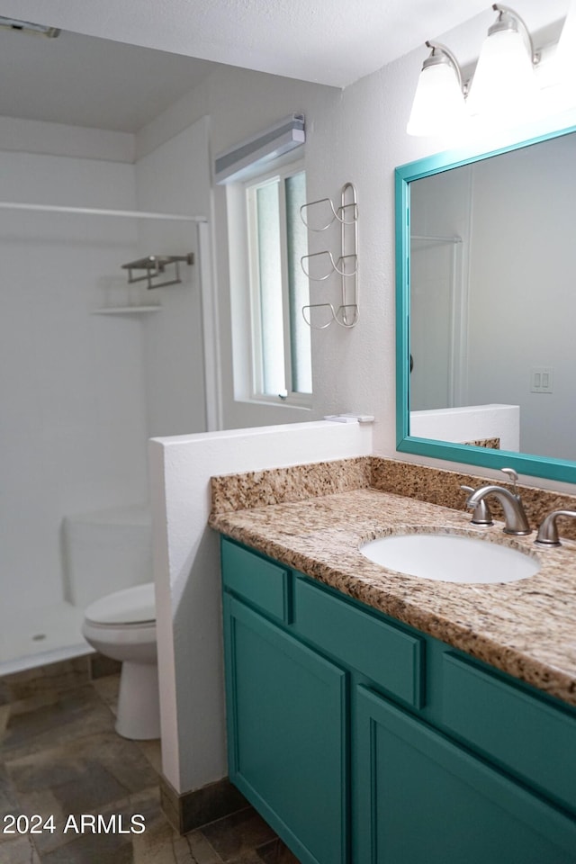 bathroom with toilet, vanity, and walk in shower