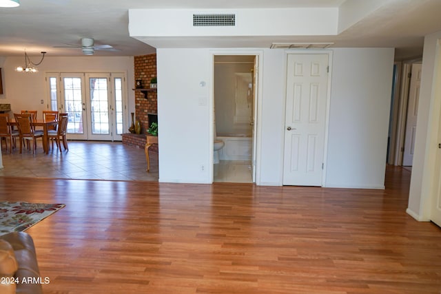 living room with french doors, ceiling fan with notable chandelier, and light wood-type flooring