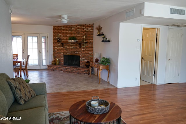 living room with a fireplace, french doors, light hardwood / wood-style flooring, and ceiling fan