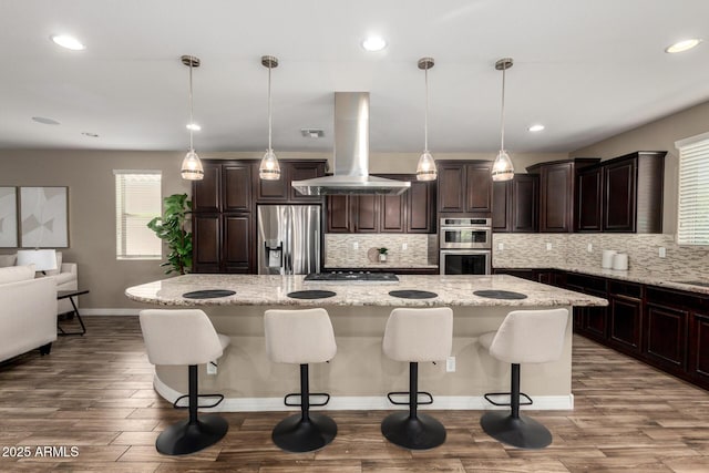 3338 E Coconino Dr, Gilbert, AZ 85298 - kitchen with appliances with stainless steel finishes, island exhaust hood, wood finished floors, decorative backsplash, and recessed lighting
