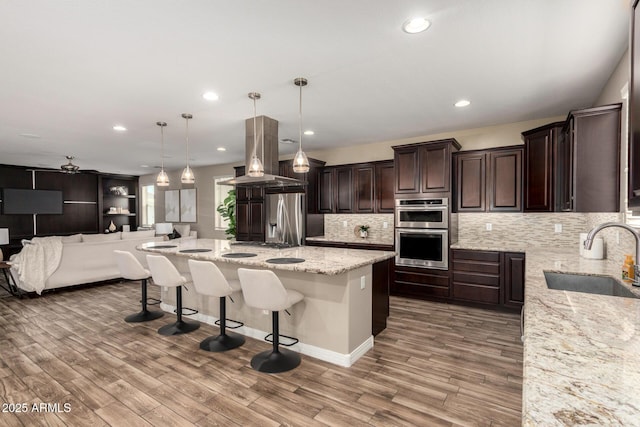 3338 E Coconino Dr, Gilbert, AZ 85298 - kitchen with appliances with stainless steel finishes, dark brown cabinets, decorative backsplash, a breakfast bar area, and recessed lighting