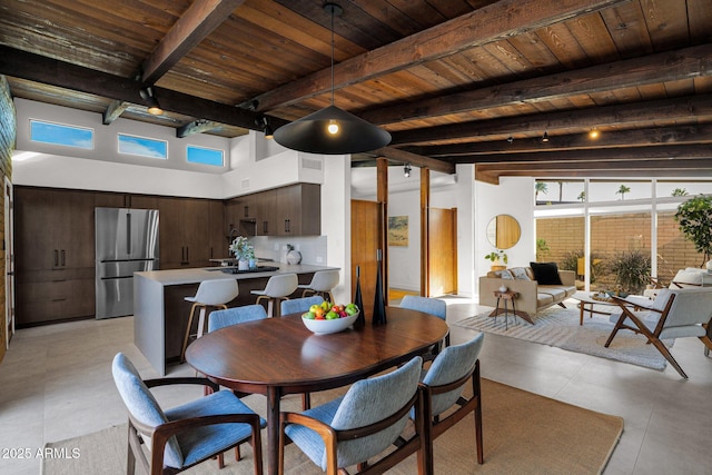 dining space with beam ceiling, wooden ceiling, and a high ceiling