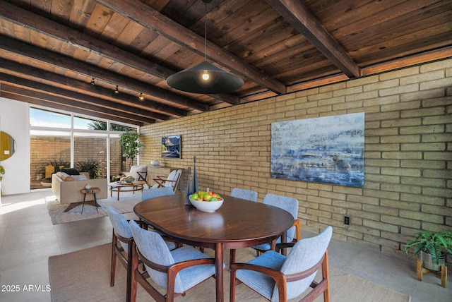 dining room with wooden ceiling, beamed ceiling, and brick wall