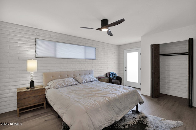 bedroom with ceiling fan, brick wall, and wood-type flooring