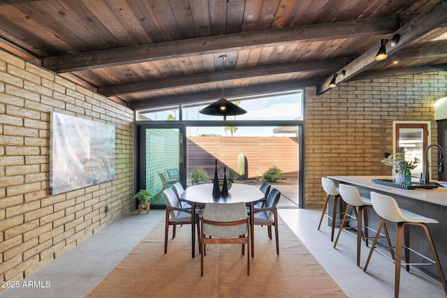 dining room featuring vaulted ceiling with beams and brick wall