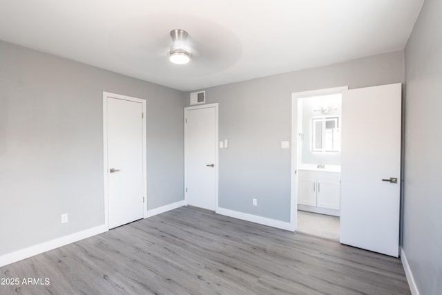 6316 N 23rd Ave, Phoenix, AZ 85015 - unfurnished bedroom featuring wood finished floors, baseboards, a sink, and ensuite bathroom