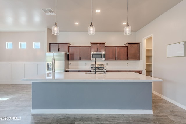 809 W Coles Rd, Phoenix, AZ 85041 - kitchen featuring stainless steel appliances, a kitchen island with sink, a sink, backsplash, and light countertops