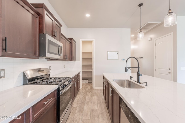 809 W Coles Rd, Phoenix, AZ 85041 - kitchen featuring appliances with stainless steel finishes, a sink, decorative backsplash, light wood-style flooring, and decorative light fixtures