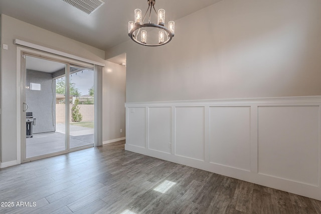 809 W Coles Rd, Phoenix, AZ 85041 - unfurnished dining area featuring a decorative wall, wood finished floors, a chandelier, and wainscoting