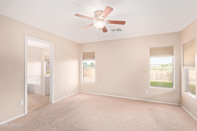 unfurnished room with ceiling fan, carpet floors, a wealth of natural light, and visible vents