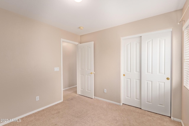 unfurnished bedroom featuring a closet, light colored carpet, and baseboards