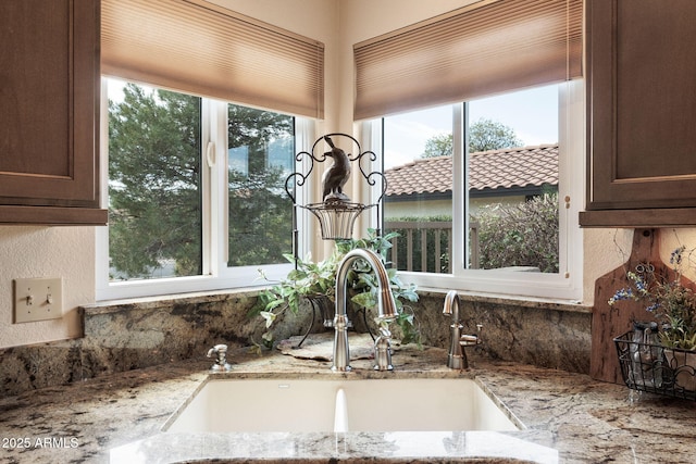 room details with a sink, decorative backsplash, and light stone countertops