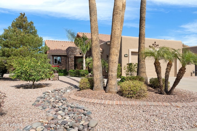 view of front facade with a garage, a tile roof, driveway, stone siding, and stucco siding