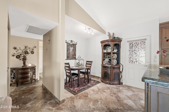 dining space featuring vaulted ceiling, stone finish floor, visible vents, and baseboards