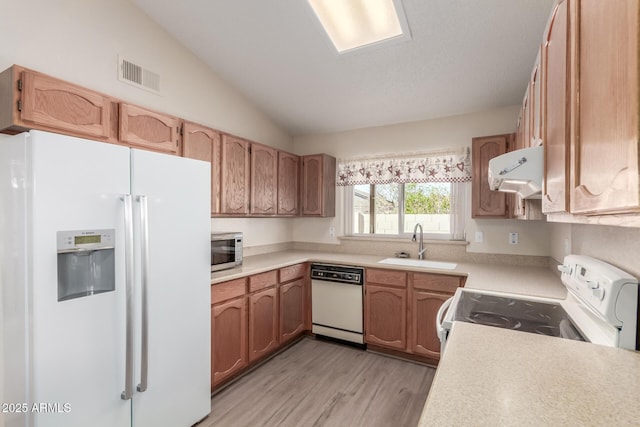 kitchen with white appliances, lofted ceiling, extractor fan, light hardwood / wood-style floors, and sink