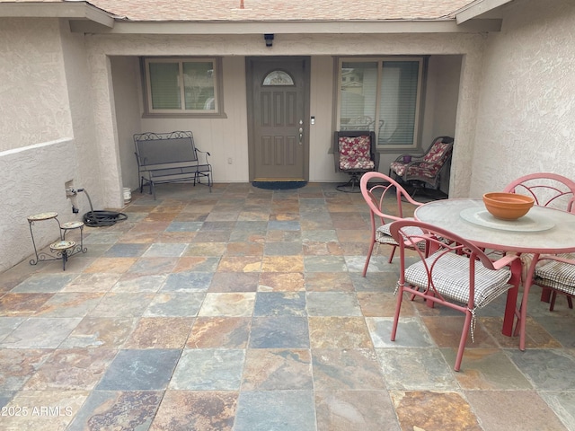 property entrance featuring a shingled roof, a patio area, and stucco siding