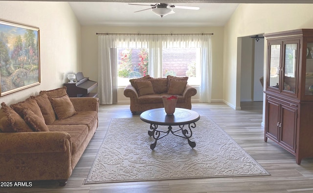 living room with lofted ceiling, light wood finished floors, and a ceiling fan