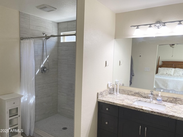 bathroom with visible vents, a textured wall, connected bathroom, a shower stall, and vanity