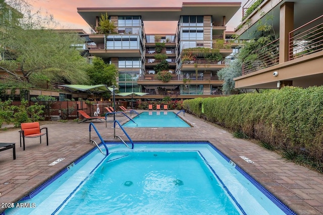 pool at dusk with a patio area