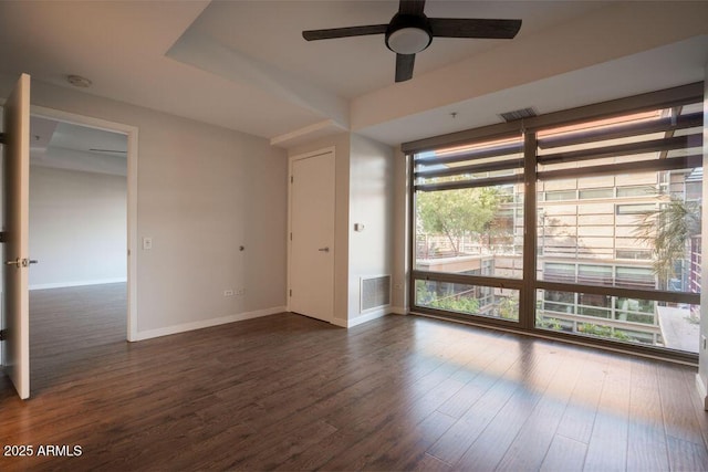 empty room with expansive windows, dark hardwood / wood-style floors, and ceiling fan