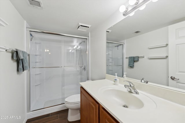 bathroom with toilet, wood finished floors, visible vents, and a shower stall